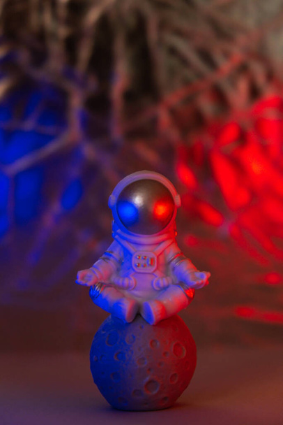 赤と青の光を持つプラスチック製のおもちゃのフィギュア宇宙飛行士コピースペース。地球旅行、民間の宇宙飛行のうちの概念。宇宙ミッションと持続可能性 - 写真・画像