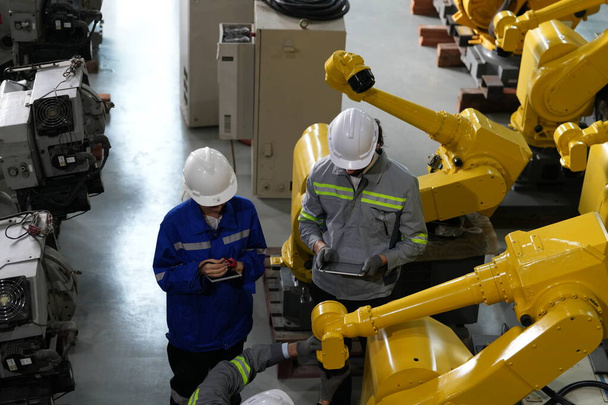 工場倉庫でロボットアームのメンテナンスを行うロボットエンジニア。事業技術. - 写真・画像