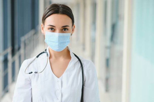 Portrait of young beautiful female medical worker,wearing uniform and protective face mask. - Φωτογραφία, εικόνα