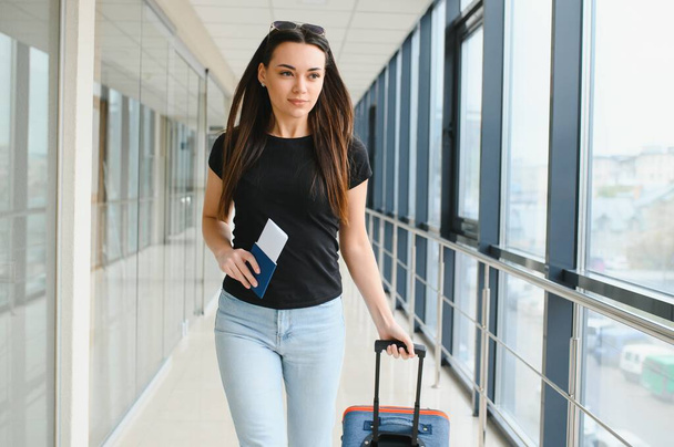 Young woman pulling suitcase in airport terminal. Copy space. - Φωτογραφία, εικόνα