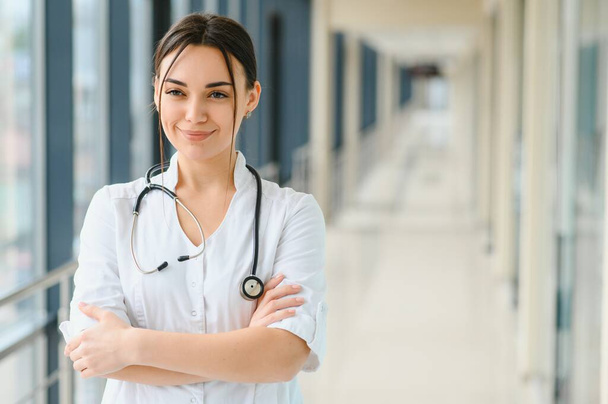 Щаслива молода жінка-лікар одягнена в уніформу, біле медичне пальто, стетоскоп. Портрет красивої жінки-лікаря, терапевта, медсестри
 - Фото, зображення