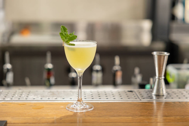 yellow cocktail with mint on the bar. restaurant serving - Фото, зображення