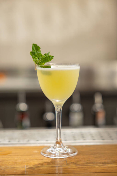 yellow cocktail with mint on the bar. restaurant serving - Fotoğraf, Görsel
