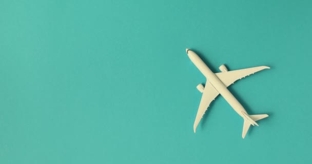 Fehér játék repülőgép türkiz háttérrel. Légi szállítás interkontinentális utazásokra. Utazási iroda koncepciója és repülőutak külföldi országokba - Felvétel, videó