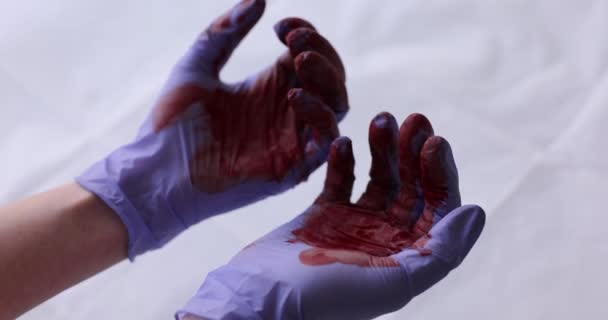 O médico mostra as mãos em luvas de borracha manchadas com sangue do paciente. Mãos de cirurgião tremendo após cirurgia difícil na clínica câmera lenta - Filmagem, Vídeo