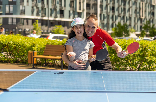 Happy man with his daughter playing ping pong in park. - Zdjęcie, obraz