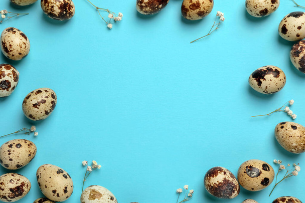 Frame made of speckled quail eggs on light blue background, flat lay. Space for text - Foto, Imagen
