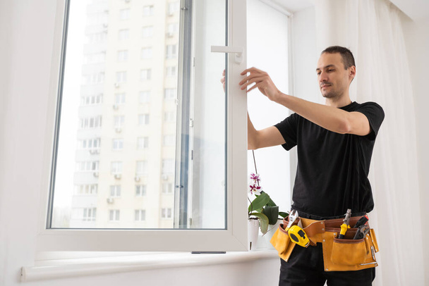 Worker adjusting installed window with screwdriver indoors, closeup. High quality photo - Valokuva, kuva
