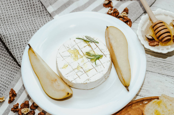 Trozos de pera madura con queso Camembert sobre la mesa. - Foto, Imagen