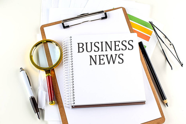 BUSINESS NEWS text on a notebook with clipboard on white background - Zdjęcie, obraz
