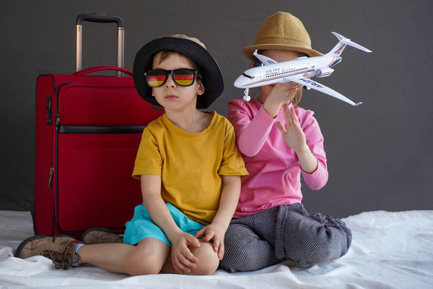 Junge und Mädchen in Sommerkleidung spielen mit dem Flugzeug. Das Konzept des Familienurlaubs im Sommer. Studioaufnahme - Foto, Bild