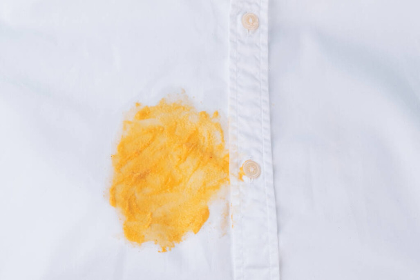Mancha amarilla sucia en una camisa blanca. Ropa estropeada. aislado. Vista superior. Foto de alta calidad - Foto, imagen