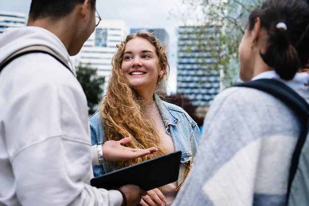 Şehirdeki şehir kampüsünde konuşan bir grup üniversite öğrencisi arkadaşları olan sarışın üniversiteli kız. - Fotoğraf, Görsel