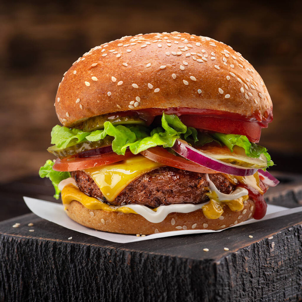 Tasty cheeseburger or hamburger on wooden tray close-up. - Φωτογραφία, εικόνα