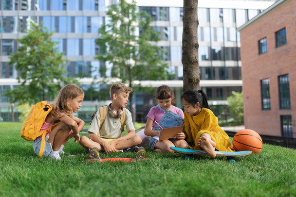 Happy kids playing and talking together in s city park, during summer day. - 写真・画像
