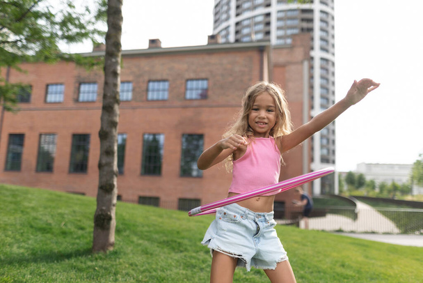 Little girl playing with hula hoop in a city park. - 写真・画像