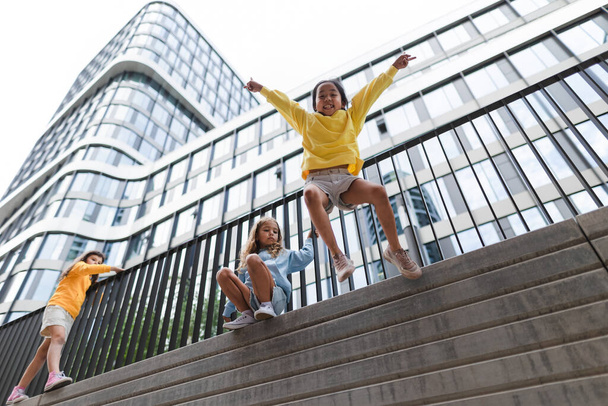 Two girls firends jumping down from concrete wall in city. Low angle view. - Fotó, kép