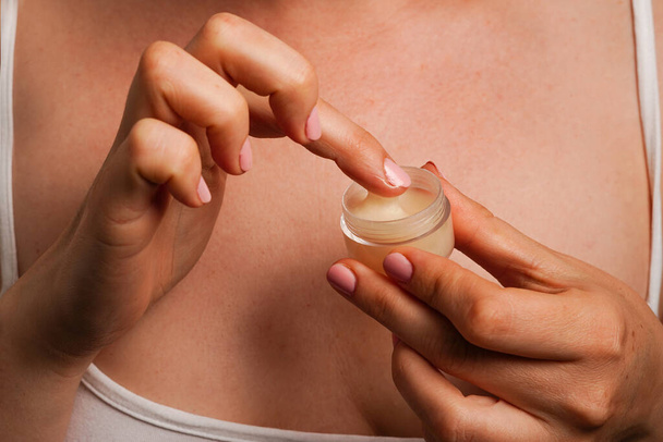 Frau hält kosmetische Creme in der Hand gegen ihren Körper, natürliche Hautpflegeprodukte - Foto, Bild