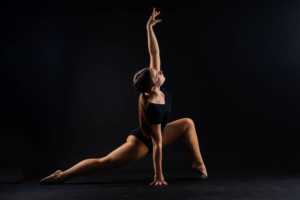Гибкая девушка, ритмичная гимнастка, прыгающая на белом темном фоне. Благодать в движении, действие. - Фото, изображение