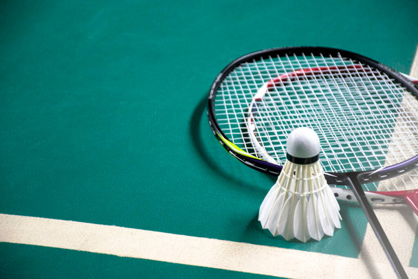 Badminton jogador detém raquete e creme branco shuttlecock na frente da rede antes de servi-lo para outro lado da quadra. - Foto, Imagem