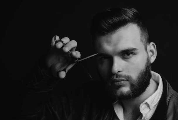 Young sexy man, portrait of guy with barber scissors for barber shop. Modern barbershop, shaving. Handsome male with modern hairstyle on black - Valokuva, kuva