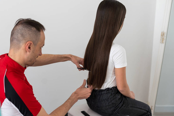 Father cutting hair of teenage daughter at home. - Photo, Image