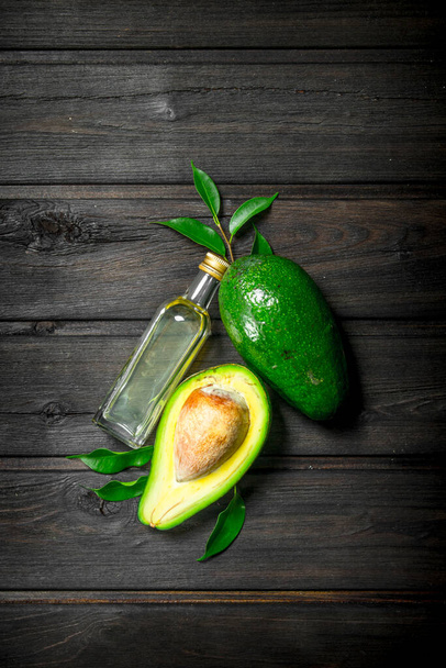 Avocado with leaves and a bottle. On a wooden background. - 写真・画像