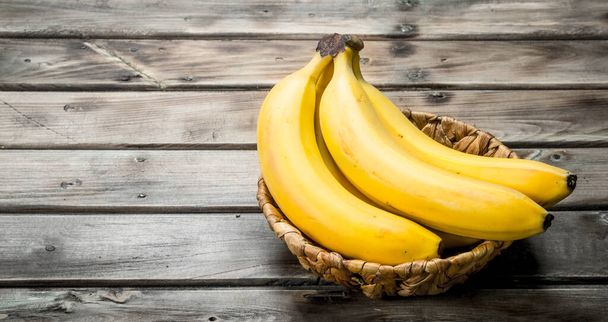 Bunch of bananas in the basket. On a black wooden background. - Photo, Image