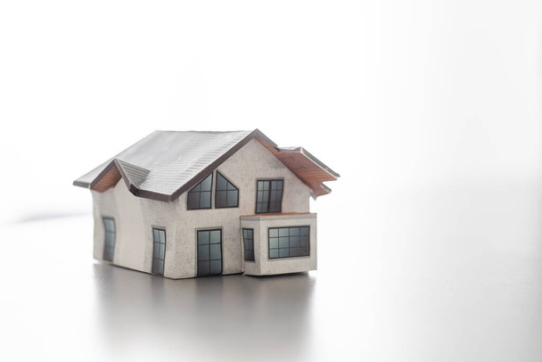 Modello di casa dipinta di bianco sotto il tetto piastrellato. - Foto, immagini