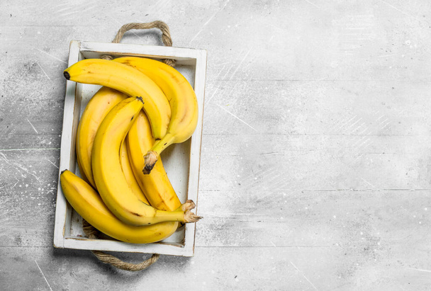 Fresh bananas in a wooden box. On white rustic background. - Fotó, kép
