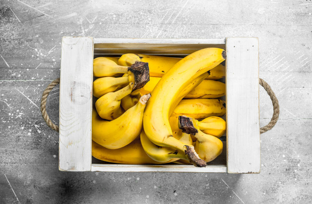 Fresh bananas in a wooden box. On white rustic background. - Photo, image