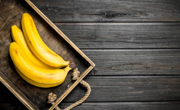 Fresh bananas in a wooden box. On a black wooden background. - Foto, Imagem