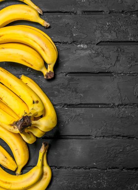 Whole fresh bananas. On black rustic background. - Photo, Image