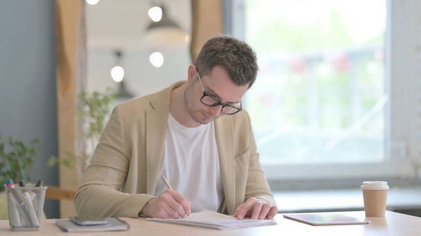 Young Businessman Doing Paperwork and Using Smartphone - Photo, Image