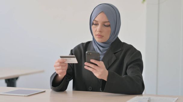 電話および銀行カードを使用してアラブビジネス女性オンラインショッピング - 写真・画像