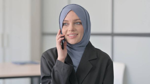 Porträt einer muslimischen Geschäftsfrau, die am Telefon spricht - Foto, Bild