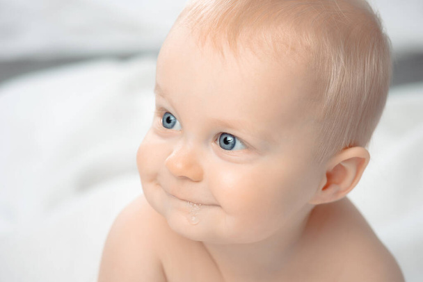 Χαριτωμένο μωρό με μπλε μάτια - κοντινό πορτρέτο. Το αγοράκι κοιτάζει αλλού.. - Φωτογραφία, εικόνα
