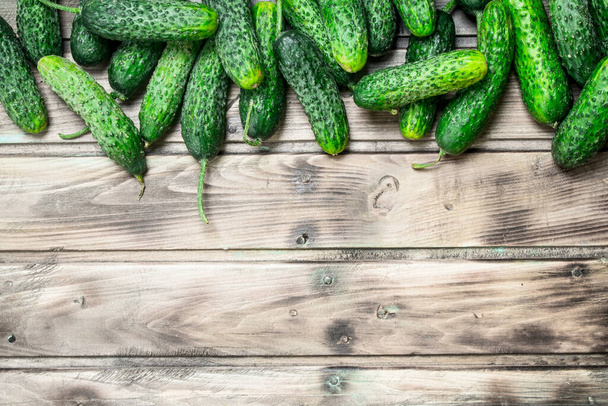 Whole fresh cucumbers. On wooden background - 写真・画像
