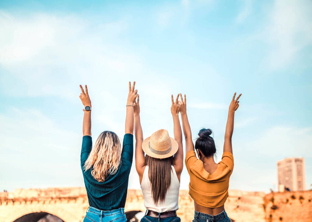 Mujeres felices con los brazos arriba al aire libre. Personas que apoyan a la comunidad. Concepto de turismo, viajes, libertad y amistad - Foto, imagen