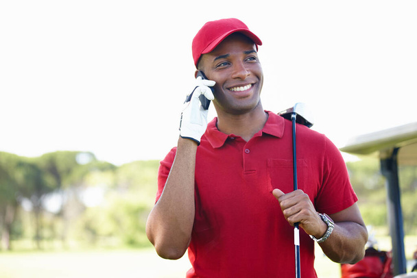 Спорим, ты жалеешь, что не здесь. молодой человек, стоящий на поле для гольфа и разговаривающий по мобильному телефону - Фото, изображение