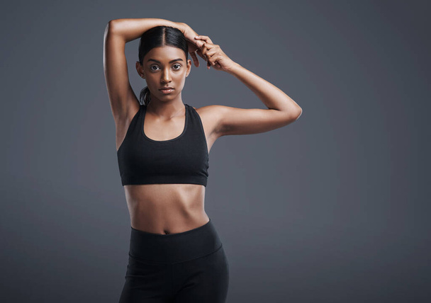 Portrait, space and stretching with an athlete woman in studio on a gray background for fitness or health. Exercise, workout or warm up and an attractive young female model training with mockup. - 写真・画像