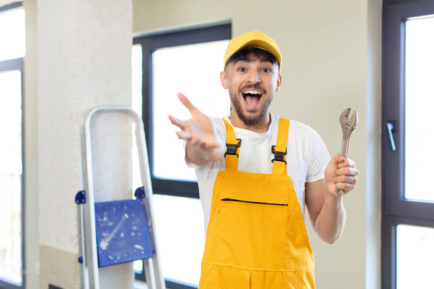 young handsome man smiling happily and offering or showing a concept. handyman concept - Photo, image