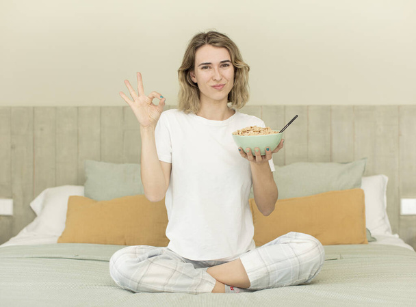 pretty woman feeling happy, showing approval with okay gesture. breakfast bowl - Fotografie, Obrázek