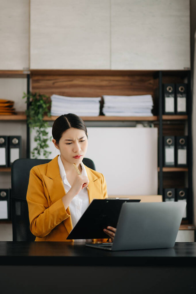Businesswoman using  laptop for doing math finance on an office desk, tax, report, accounting, statistics, and analytical research concept in modern office - Foto, Imagem