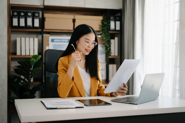 Donna d'affari asiatica che lavora in ufficio con tablet e laptop in un ufficio moderno - Foto, immagini