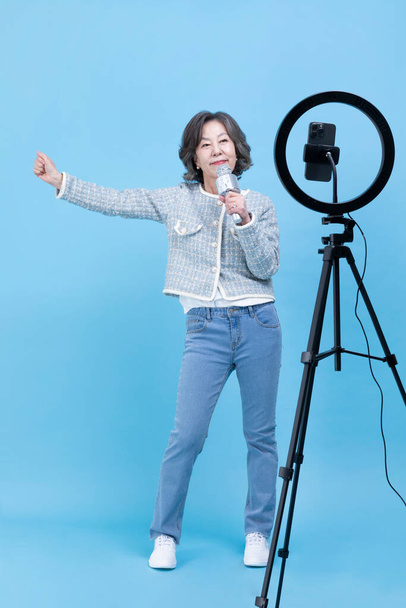 singing active young senior Korean Asian woman with smartphone, mobile karaoke concept - Foto, Imagem