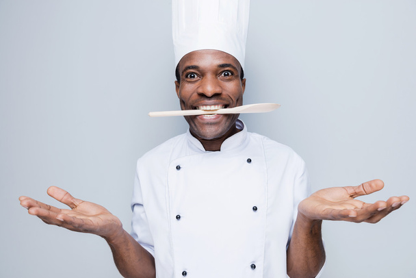 African chef holding spoon in mouth - Фото, изображение