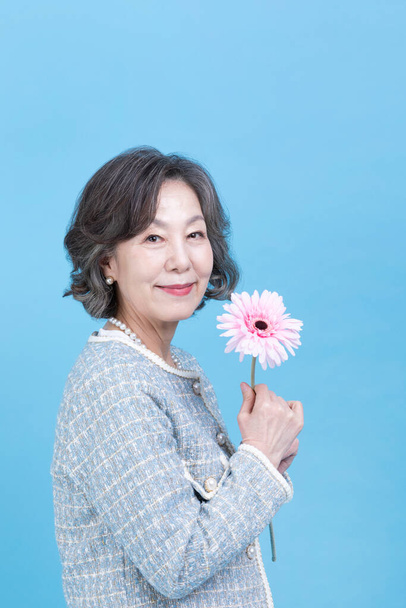active young senior Korean Asian woman holding flowers - Photo, Image