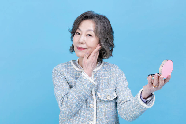 active young senior Korean Asian woman holding beauty cosmetic products - 写真・画像