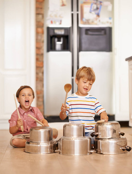 Rock, pots and drums with children in kitchen for imagination, fantasy and games. Bonding, siblings and happy with kids and kitchenware on floor of family home for music, noise and happiness. - Photo, Image